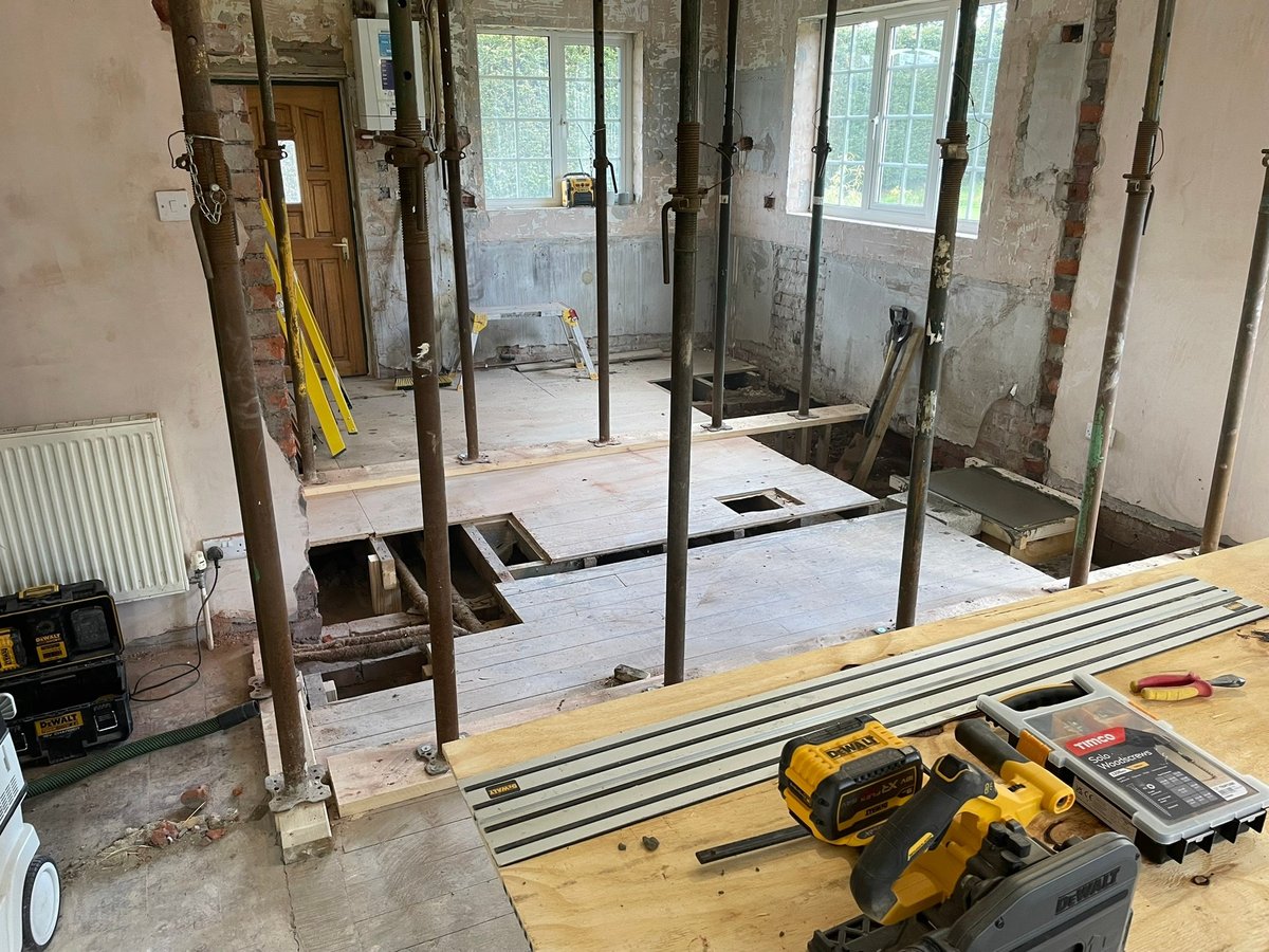 Construction site interior with shower enclosure framing, tools, and materials on work table